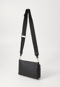 Borsa a tracolla nera in pelle con superficie testurizzata, zip dorata e cinta nera regolabile. Forma rettangolare compatta.