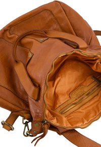 Sac à dos en cuir tan avec fermeture éclair, comportant une poche intérieure et une doublure orange contrastante. Texture lisse et bretelles robustes.