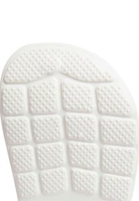 Semelle en caoutchouc blanche avec une surface texturée comportant de petits carrés surélevés pour l'adhérence, forme légèrement courbée et bords arrondis.