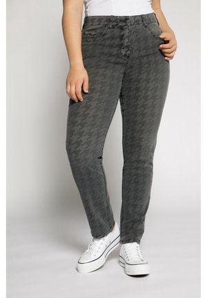 Jeans w szarym wzorze houndstooth o dopasowanym kroju, z zapięciem na guziki i suwak, oraz z kieszeniami z przodu. W połączeniu z białymi sneakerami.