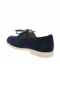 Mocassino da uomo in camoscio blu navy con suola bianca e dettaglio con lacci, angolato per mostrare il lato esterno e il tallone posteriore.