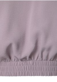 Ljuslila tyg med en mjuk textur, utrustad med en rynkad resår i midjan. Materialet verkar mjukt och lätt.