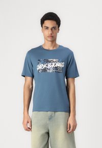 Camiseta de algodón azul con un gráfico central que muestra motivos de hojas de palma y el texto "JACK & JONES". Mangas cortas, diseño de cuello redondo.