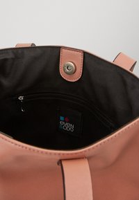 Světle růžová ekologická kožená taška s černým vnitřkem, obsahující magnetické zapínání a vnitřní kapsu na zip. Viditelná značka.