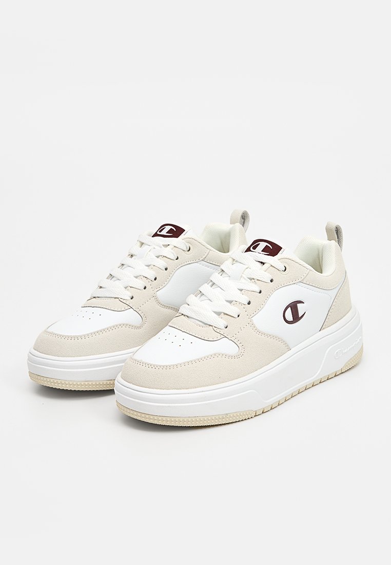 Zapatillas blancas y beige con puntera perforada, diseño de cordones, cuello acolchado y logotipo en contraste en el lateral. Suela de goma gruesa para tracción.