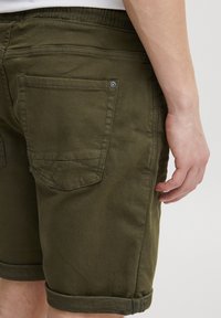 Olívazöld pamut rövidnadrág felhajtott szegéllyel, két hátsó zsebbel és finom varrási részletekkel. Puha tapintású és elasztikus derékpánttal.