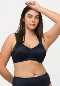 Soutien-gorge bleu marine au design sans couture, avec des bretelles larges et une texture lisse. Il présente un décolleté en V et des détails de couture subtils.