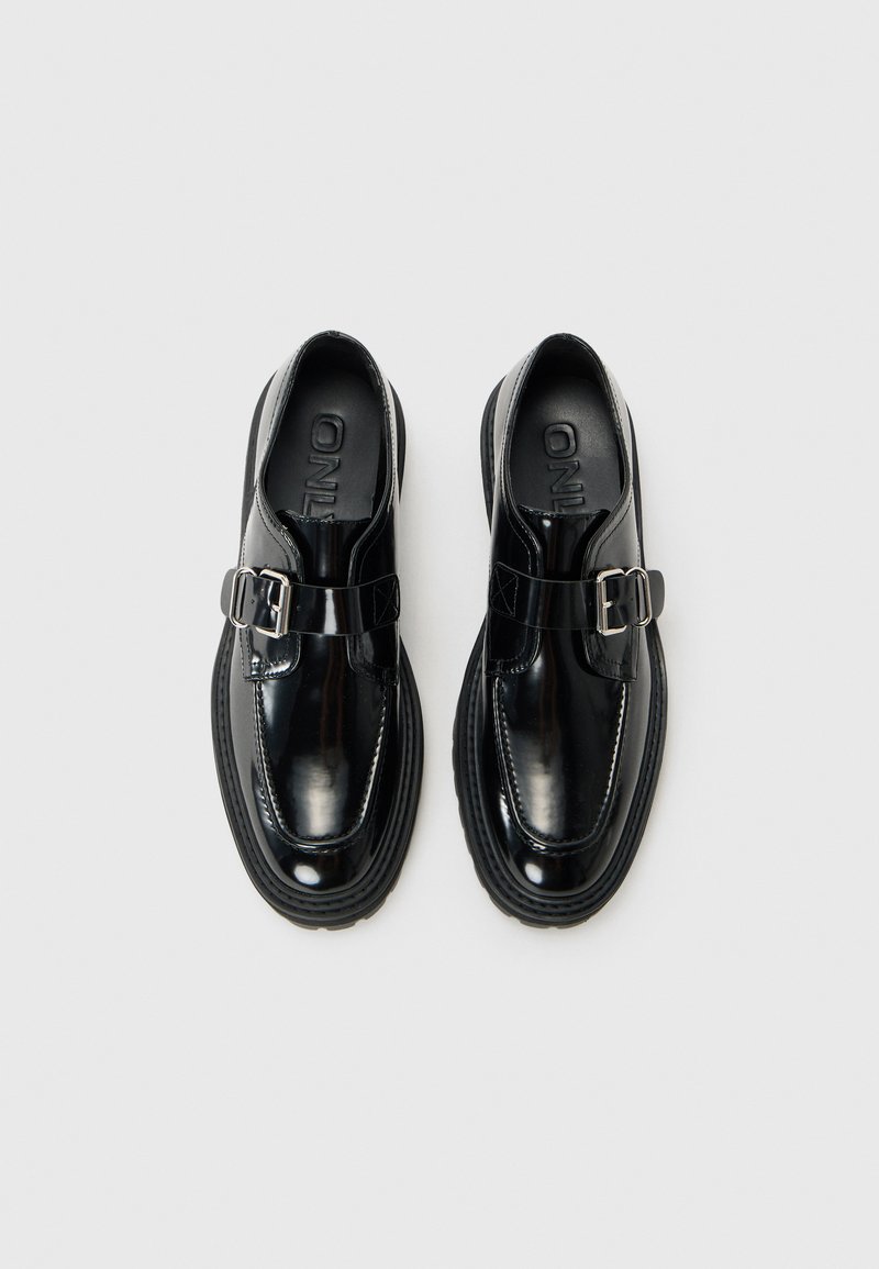 Scarpe nere lucide con cinturino a fibbia, punta tonda, suola in gomma piatta e finitura lucida. Presenti dettagli di cucitura sottili.