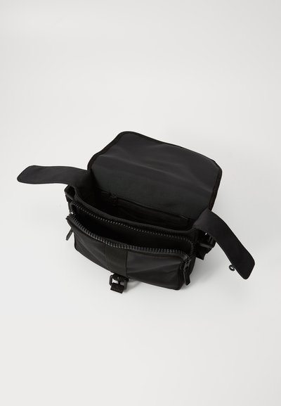 Geantă din material textil negru, cu formă pătrată, având un capac superior, două compartimente cu fermoar și o închidere cu cataramă tip clips. Textură netedă.