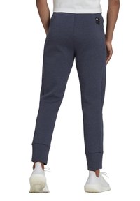 Marineblaue Jogginghose in enganliegender Passform, mit einem Logopatch auf der Rückseite und gerippten Bündchen, aus einem weichen, strukturierten Material gefertigt.