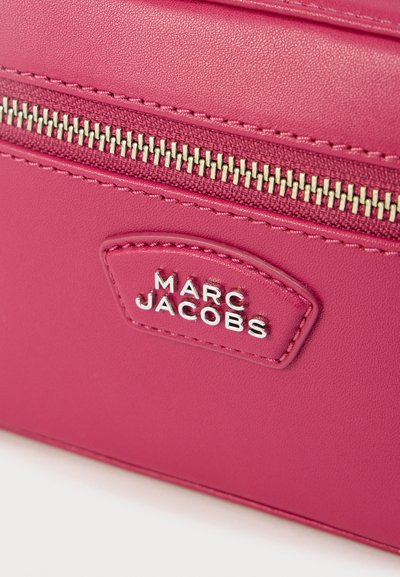Ροζ δερμάτινη τσάντα με χρυστό φερμουάρ, διαθέτει μια μικρή πλακέτα με την επιγραφή «MARC JACOBS». Λείο υλικό με ελάχιστες ραφές.