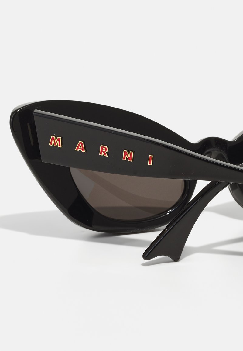 Black sunglasses with a distinctive cat-eye shape, featuring brown lenses and "MARNI" branding in red on the side. Smooth plastic material.
