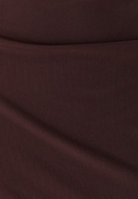 Donkerbruin textiel met een fijn gaaspatroon, soepel gedrapeerd met zachte plooien en een gelijkmatig oppervlak.