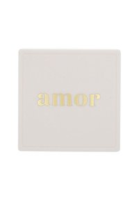 Kvadratisk keramikplatta i mjuk beige med en slät yta. Har ordet "amor" i präglad guldig text. Enkel kantaccent.