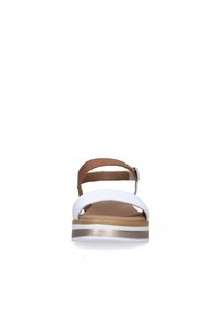 Sandal bianco con cinturino regolabile marrone, suola piatta e interno beige texturizzato. Presenta una striscia di accentatura dorata lungo la suola.