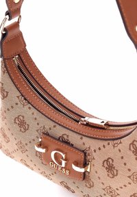 Borsa beige con motivo, rifiniture in pelle sintetica marrone, hardware dorato e accento con logo. Presenta una chiusura con zip e tracolla regolabile.