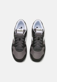 Scarpe sportive nere e grigie con tessuto in rete e suole in gomma. Accentuate da strisce bianche e un logo sulla linguetta.