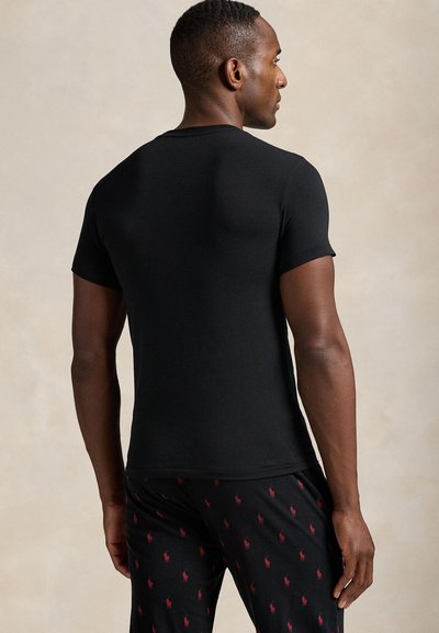 T-shirt preta de manga curta com gola redonda, feita de algodão macio, apresentando um corte justo e textura suave, combinada com calças de pijama estampadas.