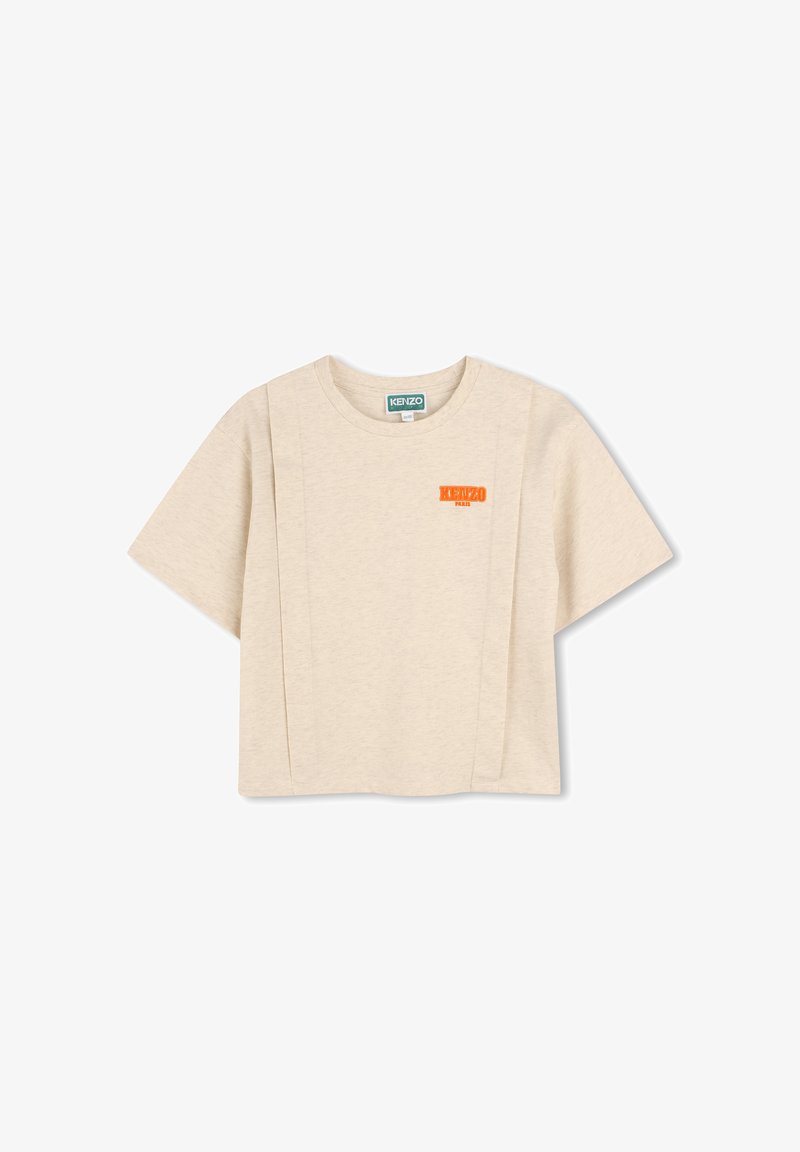 T-shirt cropped beige en coton, avec un col rond, des manches courtes et un logo orange sur la poitrine. Texture lisse.