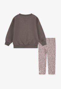 Pilkos medvilnės sportinis megztinis su raštuotais rankogaliais ir iškirpte, derinamas su rožiniais leginsais, turinčiais subtilų juodą taškuotą raštą.