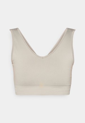Beige sømløs bralette med dyp V-hals, brede stropper og en elastisk underdel. Glatt tekstur og minimalistisk design uten synlige festemidler.