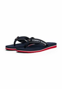 Infradito navy con cinturini in tessuto che presentano il logo "TOMMY HILFIGER", dettagli rosso e bianco sulla suola, plantare in gomma con perforazioni.