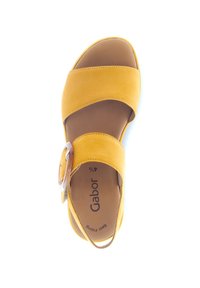 Sandal en daim jaune avec une large sangle, détail de boucle réglable, et semelle intérieure rembourrée marron. Texture lisse et design à bout rond.