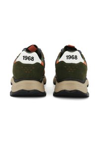 Des chaussures de sport vertes et brunes avec des accents de talon blancs, des détails en orange vif, en daim texturé et une semelle en caoutchouc. Le numéro "1968" est présent sur les talons.