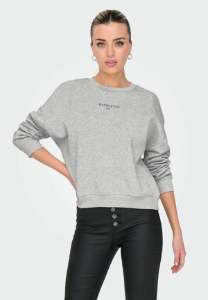 Sweatshirt gris en tissu doux, avec un col rond et des poignets côtelés. Logo "MANHATTAN NYC" en impression foncée à l'avant.