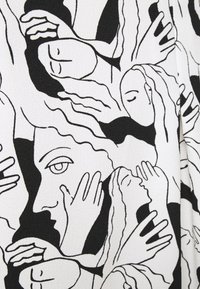 Tessuto in bianco e nero con un design astratto di volti e mani, con linee fluide ed espressioni variate che creano texture e profondità visiva.