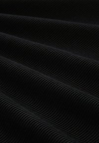 Schwarzer gerippter Textilstoff mit welliger Textur und variierenden Falten. Das Material wirkt dick und robust mit einem durchgehend gleichmäßigen Muster.