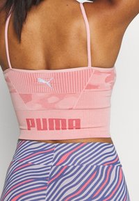 Rosa kortärmad sporttopp med meshtextur och tunna axelband, med en vit Puma-logotyp och röda blockbokstäver vid fållen.