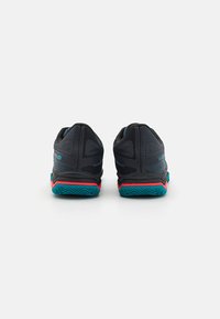 Czarne buty sportowe z teksturowaną cholewką, turkusową podeszwą i czerwonymi akcentami. Posiadają amortyzowaną piętę oraz wzmocniony czubek dla lepszego wsparcia.