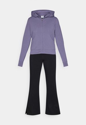 Sudadera con cremallera en color púrpura, con capucha y bolsillos frontales, combinada con pantalones de campana negros que presentan un diseño elegante y una textura suave.