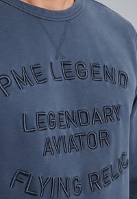 Tamno plavi dukserica od pamuka s uzdignutim izvezenim tekstom: "PME LEGEND LEGENDARY AVIATOR FLYING RELIC." Rebrasti izrez.