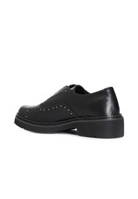 Scarpe in pelle nera con punta arrotondata, decorate con piccole borchie. Suola spessa con bordo testurizzato, che offre un design a tacco basso.