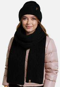 Conjunto de gorro y bufanda de punto negro, con textura acanalada. La bufanda es ancha y larga, con un detalle de acento en cuero. Diseño cálido y acogedor.