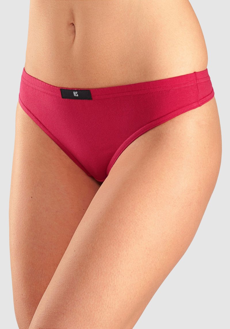 Sarkans kokvilnas bikini apakšdaļa ar gludu tekstūru, zemu vidukli un minimālu segumu, kurai ir mazs melns zīmola etiķete uz jostas.