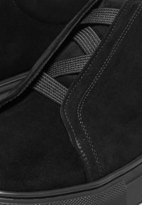 Schwarze Wildleder-Stiefeletten mit elastischen Riemen, strukturierter schwarzer Sohle und kontrastierenden Nähten. Schlankes Design mit glatter, weicher Oberfläche.