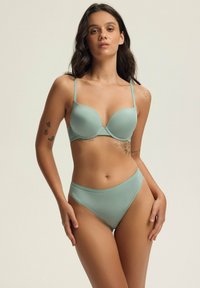 Jasnozielony komplet biustonosza i majtek z wysokim stanem. Gładki, elastyczny materiał z cienkimi ramiączkami i bezszwowym designem. Minimalistyczny styl.