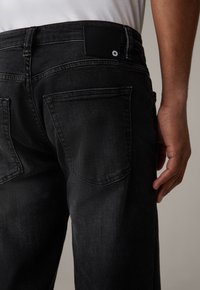 Schwarze Jeans aus Denim mit geradem Schnitt, ausgestattet mit zwei Gesäßtaschen und einem schwarzen Lederpatch am Bund mit Logodetail.