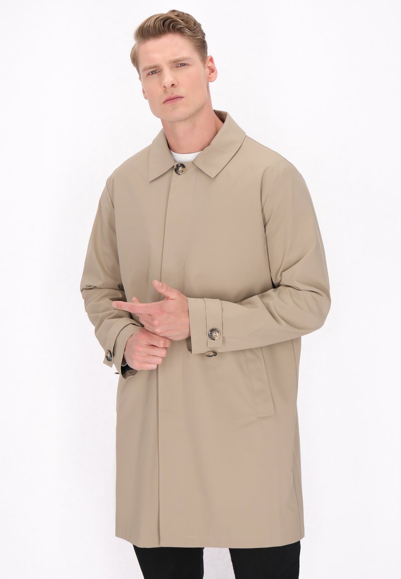 Beige vandafvisende frakke med klassisk krave, knaplukninger og sidelommer. Glat tekstur; knælangt design for let dækning.