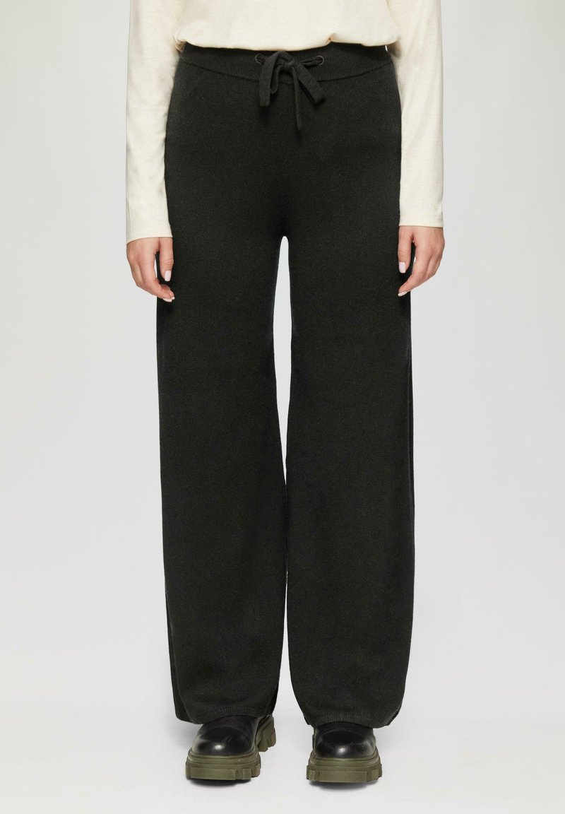 Wijd-uitlopende broek in donkergroen materiaal, met een trekkoord in de taille, zachte textuur en ribbels aan de manchetten. Versterkt met zwarte chunky laarzen.