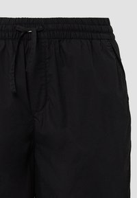 Schwarze Shorts mit elastischem Bund, Zugband, seitlichen Taschen, leichtem Stoff und glatter, matter Textur.