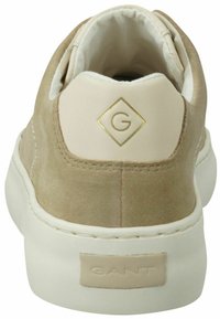 Beige suede sneaker with a white rubber sole, featuring a gold logo on a smooth leather heel and a padded collar for comfort.