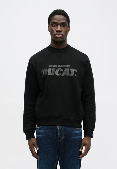 Zwarte sweatshirt met ribbelboorden en een ribbelneklijn. Voorzien van gedurfde, reliëf tekst "DSQUARED2" en "DUCATI" op de voorkant. G gedragen met blauwe jeans.