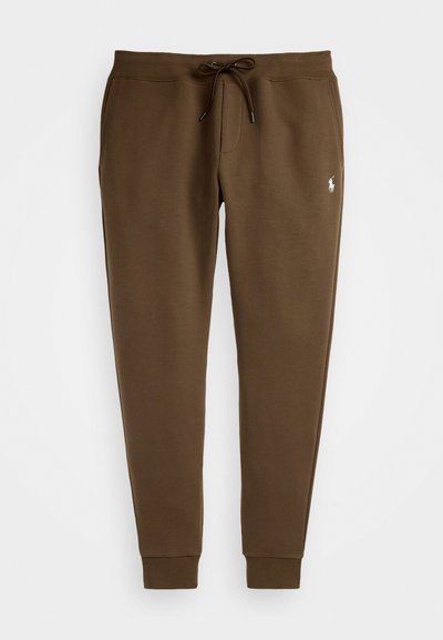 Brūni kokvilnas joggeri ar elastīgu jostu un auklu, ar apkaklēm uz potītēm un mazu izšūtu logo uz kreisās jakas.