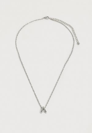 Collier chaîne en argent avec pendentif en forme de lettre majuscule « A » et fermoir ajustable sur un fond blanc uni.