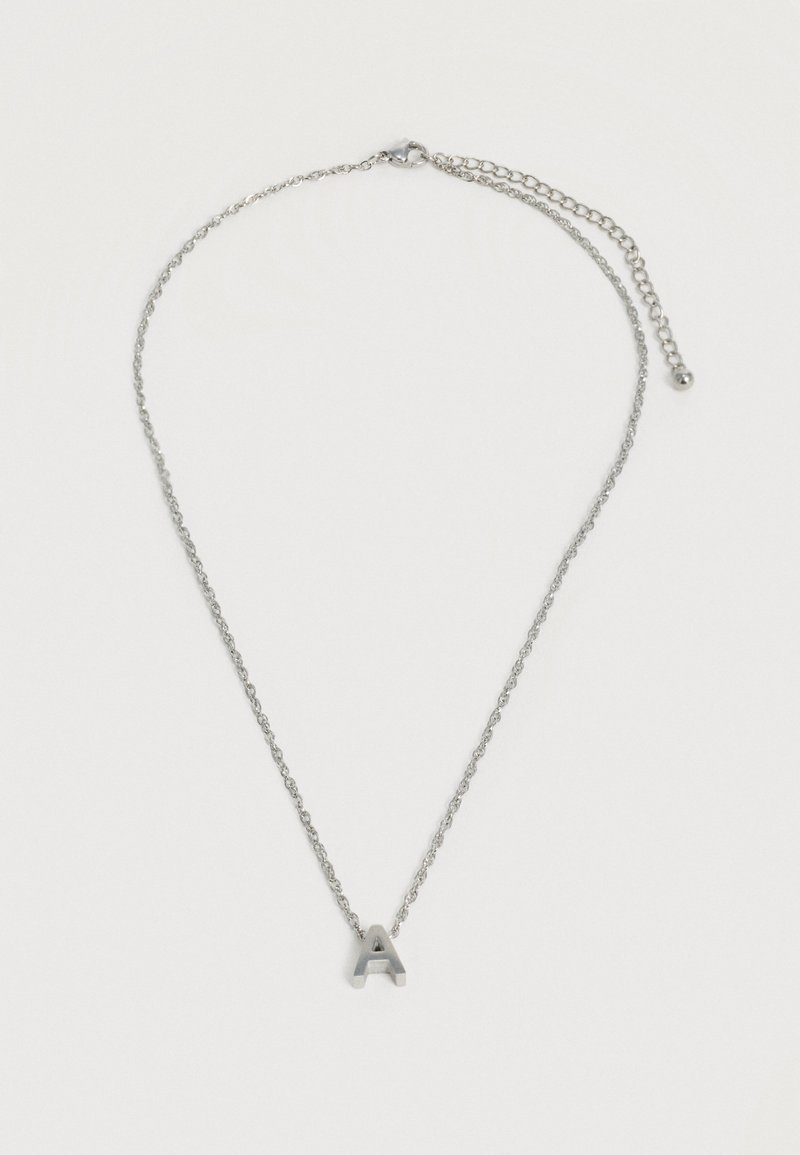 Collier chaîne en argent avec pendentif en forme de lettre majuscule « A » et fermoir ajustable sur un fond blanc uni.