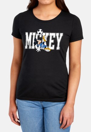 Woman wearing a black t-shirt with "MICKEY" text and a cartoon character balancing a soccer ball on its foot.